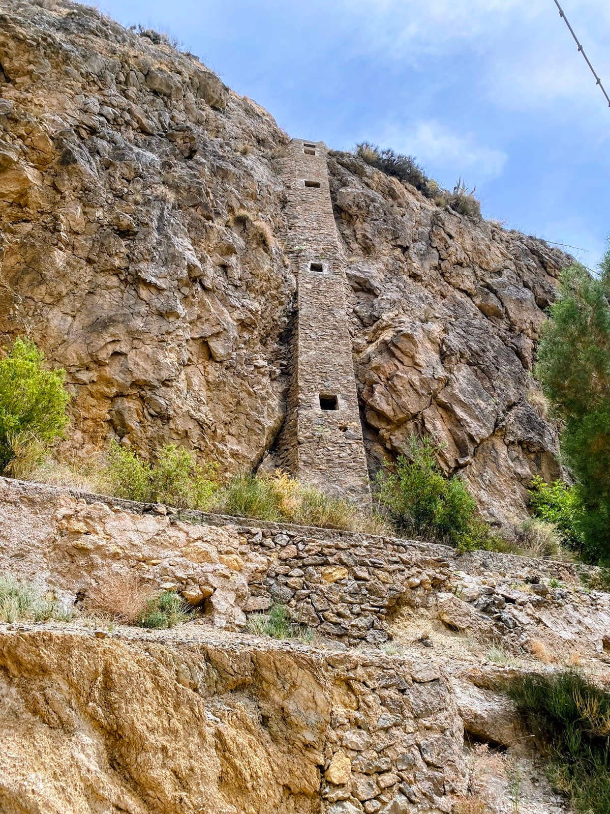 Torre de piedra encajada en la pared rocosa de un barranco